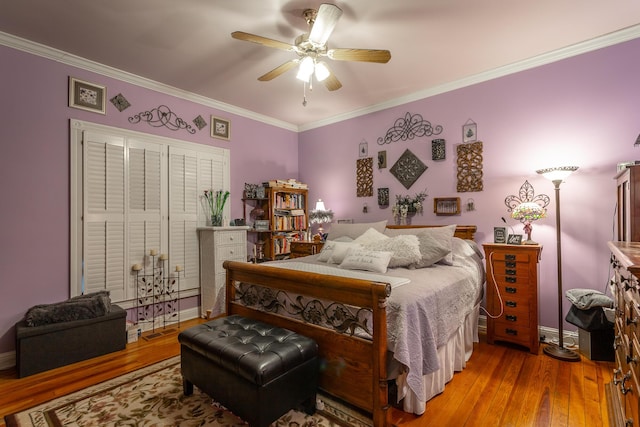 bedroom with a ceiling fan, crown molding, baseboards, and wood finished floors