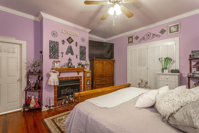 bedroom with a ceiling fan, ornamental molding, wood finished floors, and a tile fireplace