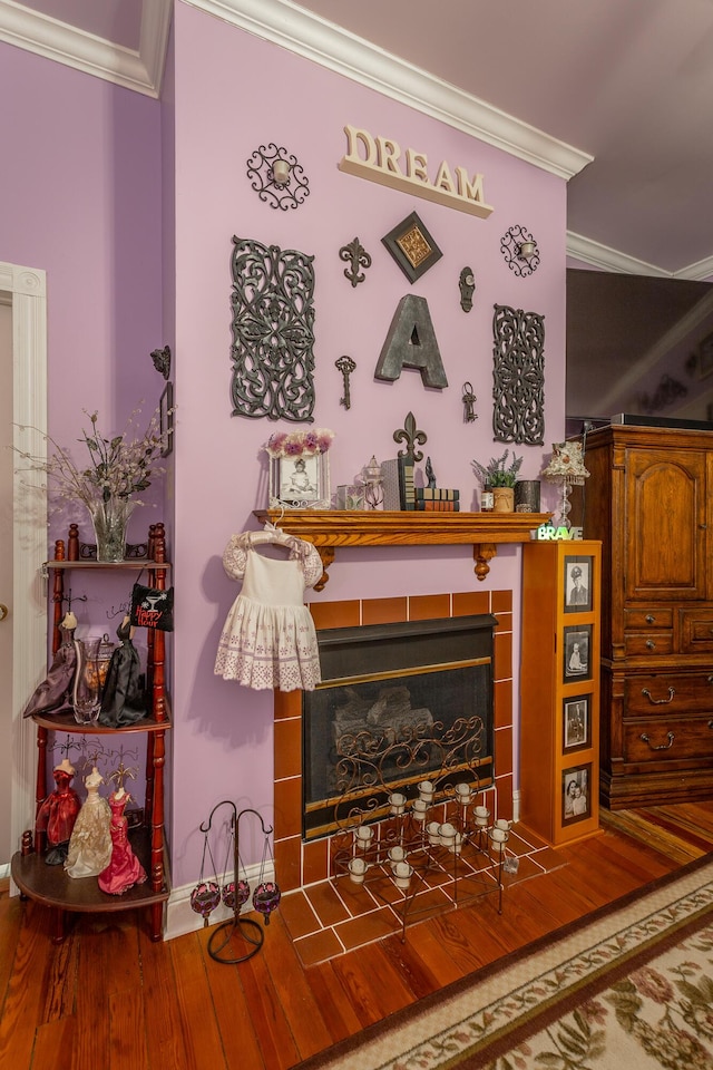 room details featuring ornamental molding, a fireplace, and wood finished floors