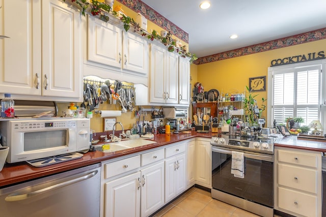 kitchen with light tile patterned floors, recessed lighting, a sink, white cabinets, and appliances with stainless steel finishes