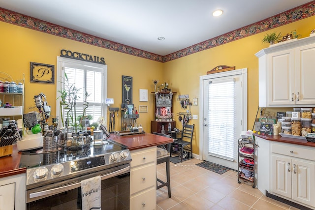 kitchen with light tile patterned floors, recessed lighting, white cabinets, and stainless steel electric stove