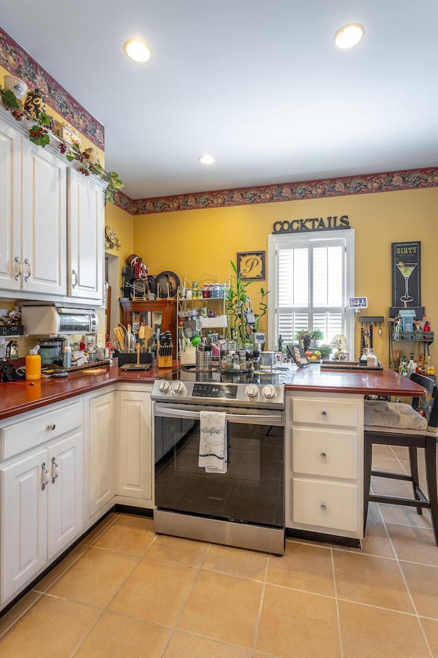 kitchen featuring recessed lighting, electric stove, white cabinets, and light tile patterned floors