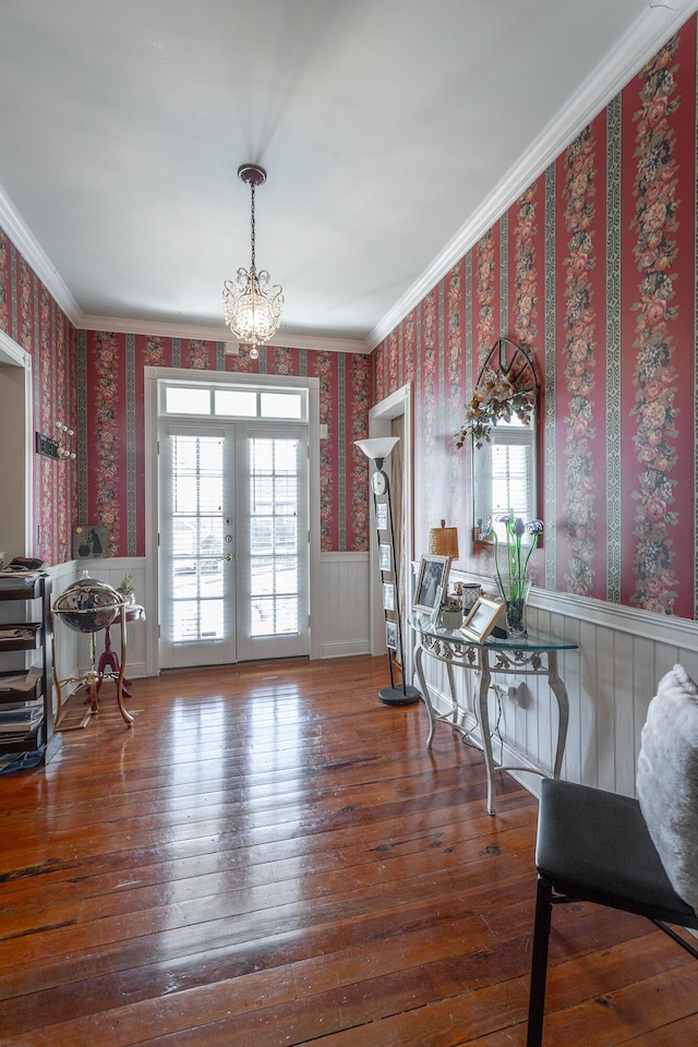 dining space with french doors, a wainscoted wall, crown molding, hardwood / wood-style floors, and wallpapered walls