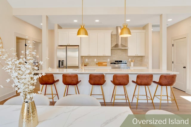 kitchen with stainless steel appliances, a sink, light wood-type flooring, wall chimney exhaust hood, and tasteful backsplash