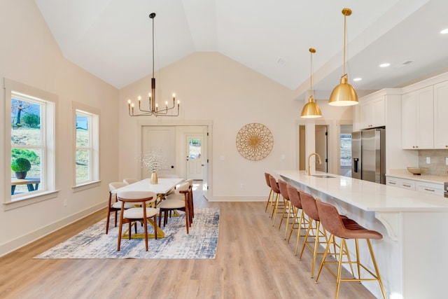 dining area featuring baseboards, light wood-style flooring, high vaulted ceiling, a notable chandelier, and recessed lighting