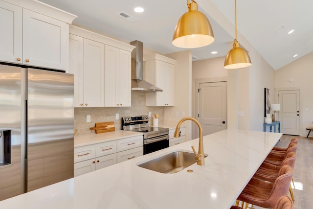 kitchen with wall chimney exhaust hood, stainless steel appliances, a sink, wood finished floors, and a kitchen breakfast bar