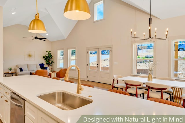 kitchen with light wood finished floors, white cabinets, a sink, light countertops, and stainless steel dishwasher