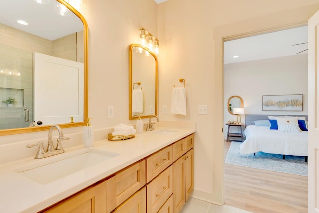 ensuite bathroom with double vanity, a shower with door, ensuite bath, and a sink