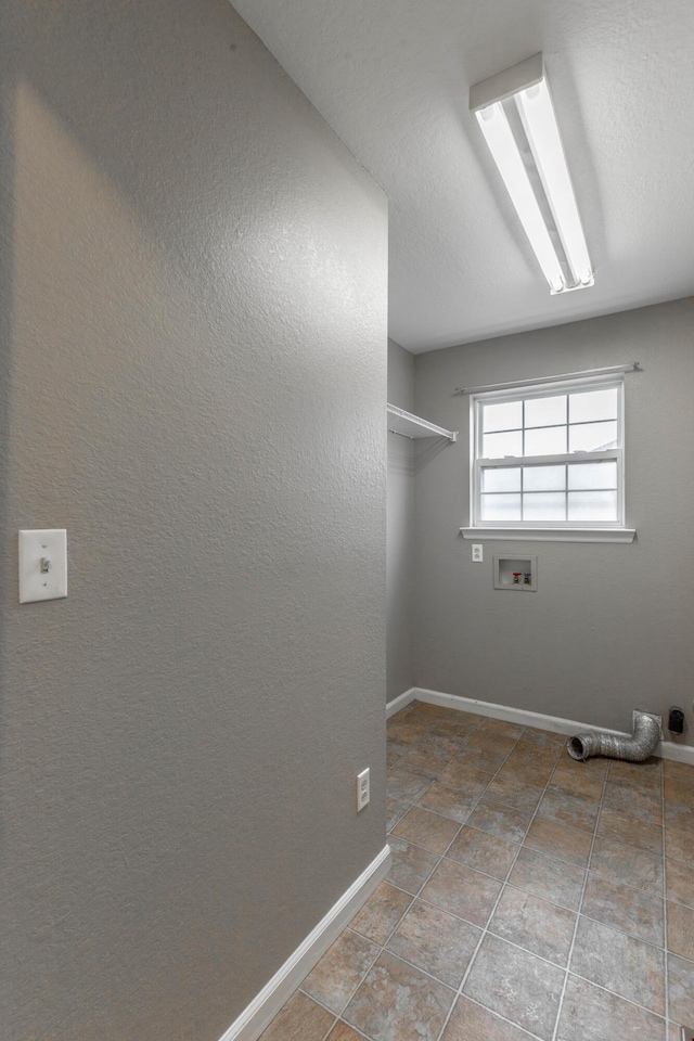 laundry area with hookup for a washing machine, a textured wall, tile patterned flooring, laundry area, and baseboards