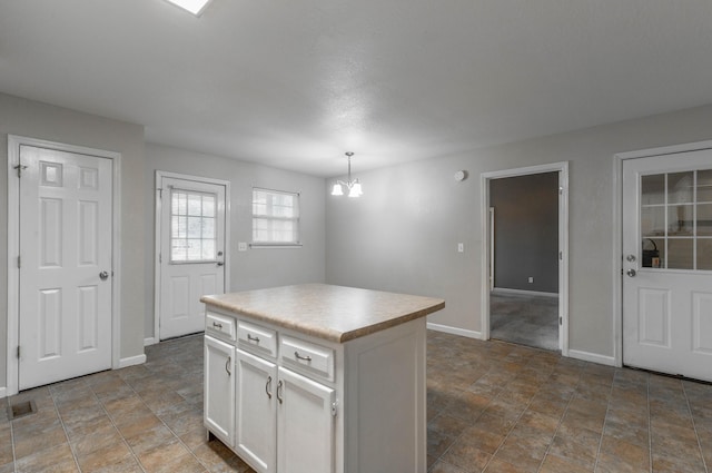 kitchen with visible vents, white cabinetry, light countertops, a center island, and an inviting chandelier