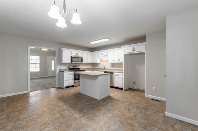 kitchen featuring appliances with stainless steel finishes, a center island, white cabinets, and a sink