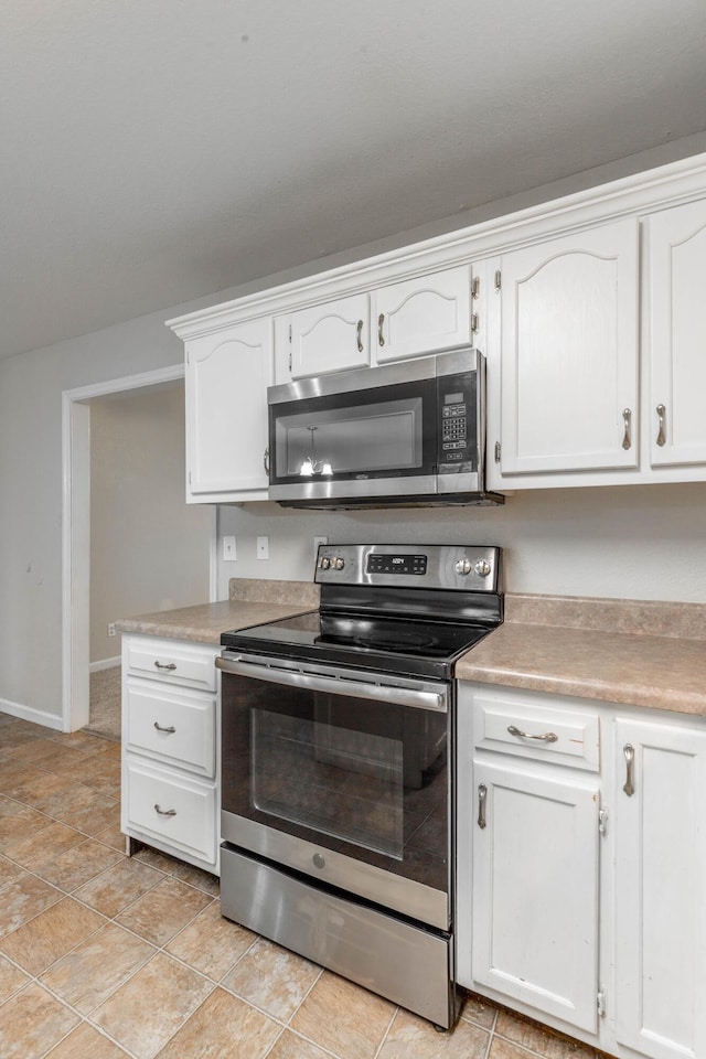 kitchen with stainless steel appliances, light countertops, white cabinetry, and baseboards