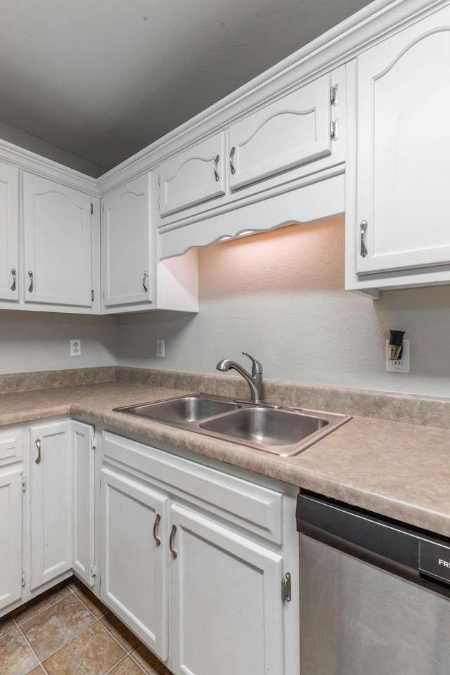 kitchen with light tile patterned floors, a sink, white cabinetry, light countertops, and dishwasher