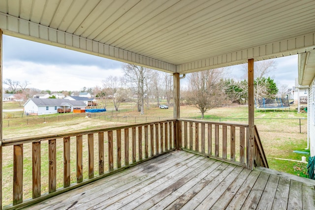 wooden deck featuring a trampoline, a yard, and fence