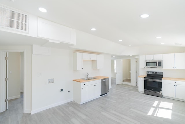 kitchen with lofted ceiling, visible vents, appliances with stainless steel finishes, white cabinetry, and a sink