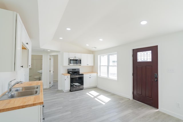 kitchen featuring appliances with stainless steel finishes, white cabinets, a sink, and wooden counters