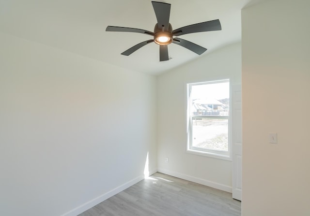 spare room with ceiling fan, light wood-style flooring, baseboards, and vaulted ceiling