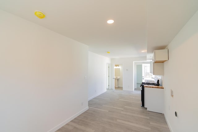 hallway with recessed lighting, light wood-type flooring, and baseboards