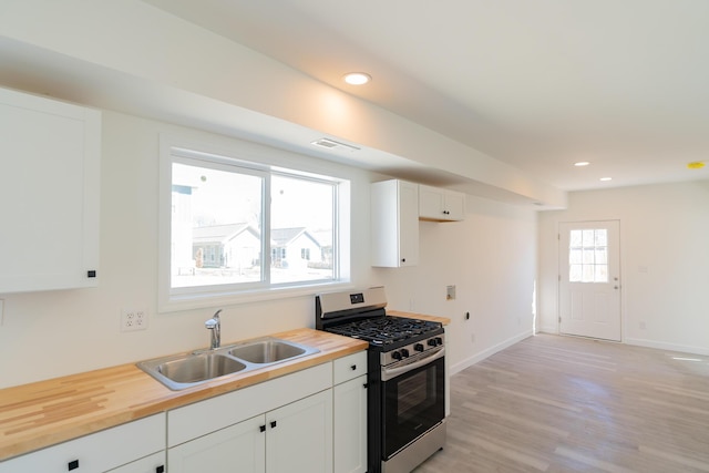 kitchen with baseboards, stainless steel gas range, wooden counters, a sink, and recessed lighting