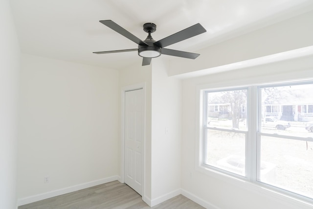 unfurnished bedroom with light wood-style floors, multiple windows, ceiling fan, and baseboards