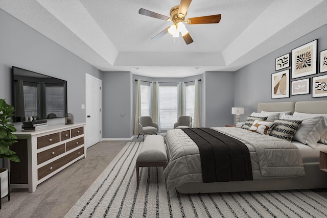 bedroom featuring a textured ceiling, baseboards, a raised ceiling, and carpet flooring