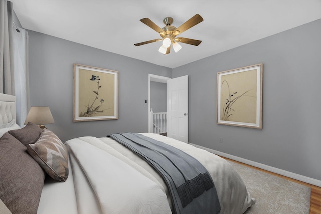 bedroom featuring wood finished floors, a ceiling fan, and baseboards