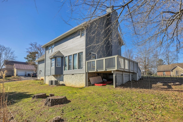 back of house featuring an outbuilding, a chimney, a lawn, fence, and a wooden deck