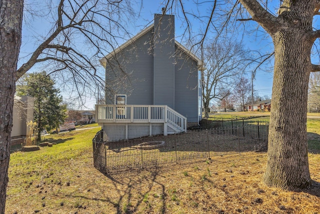 view of side of property with fence, a chimney, and a wooden deck