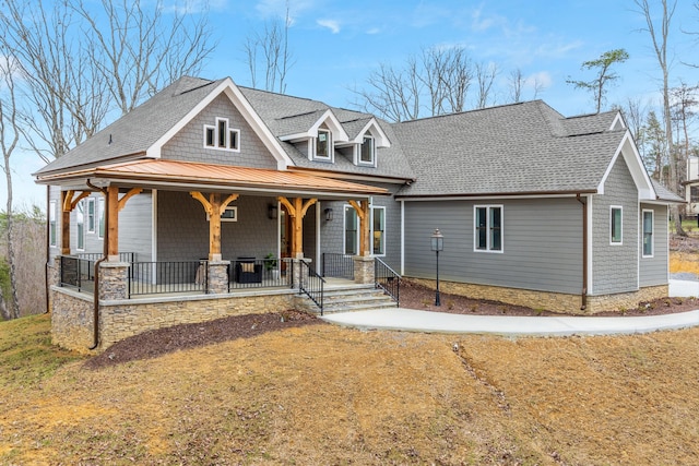 view of front facade with covered porch, a standing seam roof, metal roof, and roof with shingles