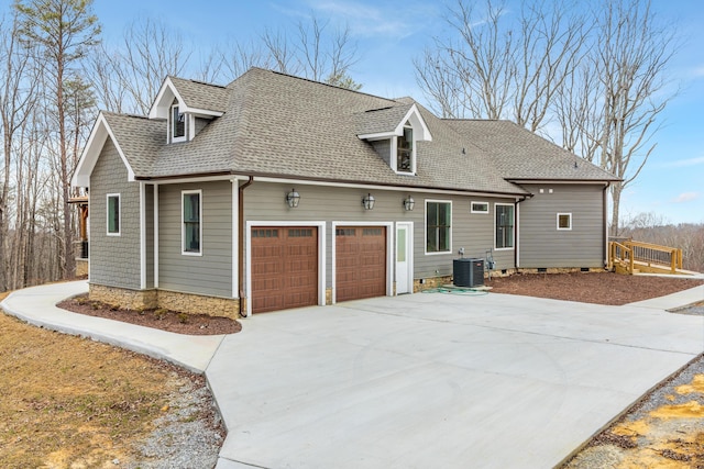 exterior space featuring a shingled roof, central AC unit, concrete driveway, an attached garage, and crawl space