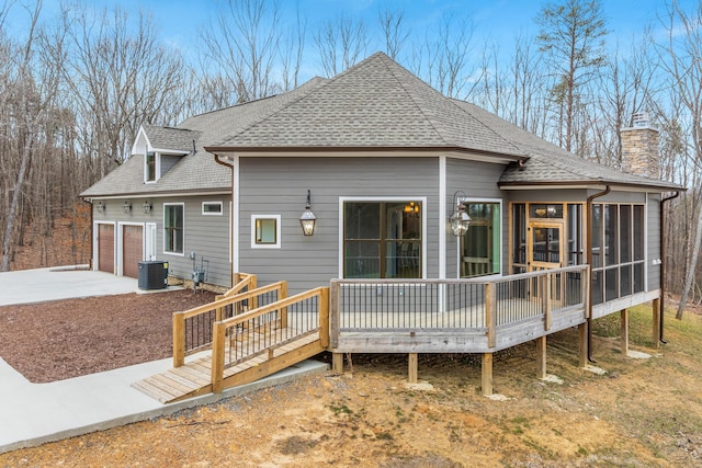 back of property featuring a shingled roof, a chimney, a sunroom, and central air condition unit