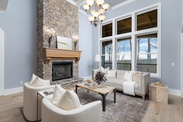 living room with a towering ceiling, a fireplace, ornamental molding, and wood finished floors