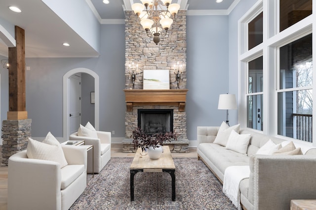 living room featuring arched walkways, crown molding, recessed lighting, a stone fireplace, and wood finished floors