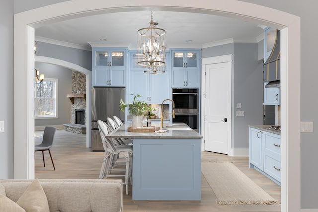 kitchen with glass insert cabinets, decorative light fixtures, stainless steel appliances, crown molding, and a sink