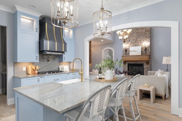 kitchen featuring crown molding, tasteful backsplash, custom range hood, stainless steel gas stovetop, and light stone countertops