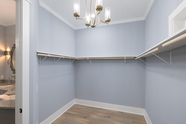 walk in closet with a notable chandelier and wood finished floors