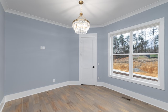 unfurnished room with crown molding, wood finished floors, visible vents, baseboards, and an inviting chandelier