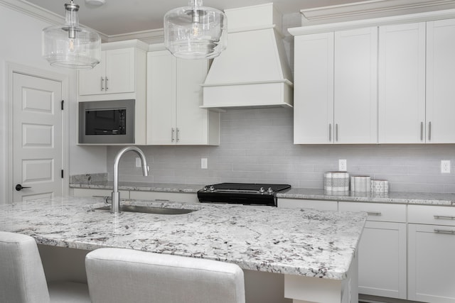 kitchen with stove, a sink, custom exhaust hood, backsplash, and stainless steel microwave