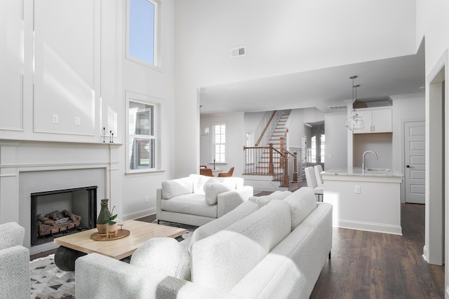 living room with baseboards, visible vents, dark wood-style floors, stairway, and a fireplace