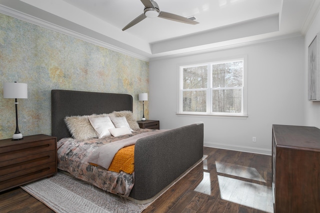 bedroom featuring hardwood / wood-style flooring, a ceiling fan, baseboards, a raised ceiling, and crown molding