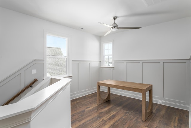 home office featuring dark wood-type flooring, a wainscoted wall, visible vents, and a ceiling fan