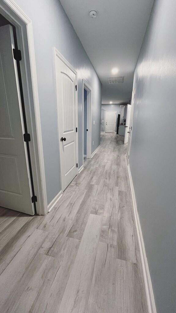 corridor with light wood-style flooring and baseboards