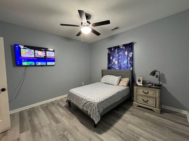 bedroom featuring baseboards, visible vents, ceiling fan, and wood finished floors