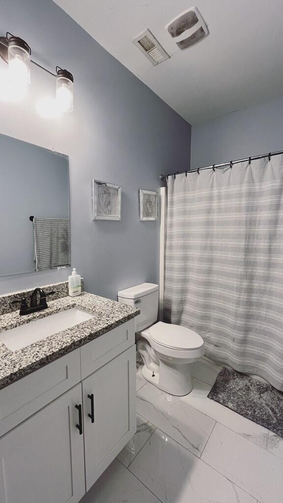 full bath with toilet, marble finish floor, vanity, and visible vents