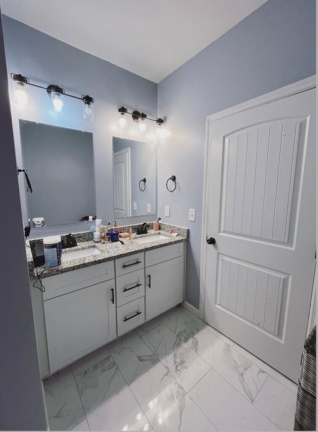 bathroom featuring marble finish floor, double vanity, and a sink