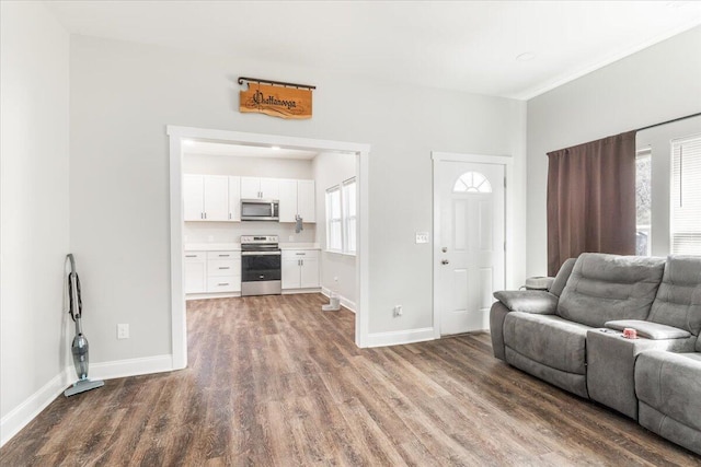 unfurnished living room featuring wood finished floors and baseboards