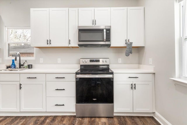 kitchen with a sink, stainless steel appliances, white cabinets, and dark wood-style flooring