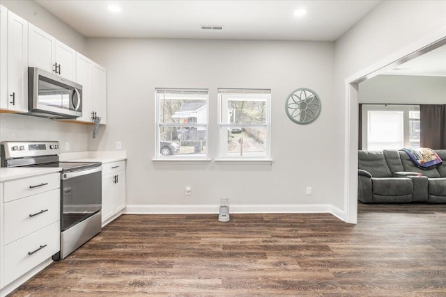 kitchen featuring plenty of natural light, appliances with stainless steel finishes, dark wood-style floors, and white cabinets