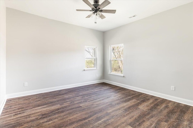 spare room featuring dark wood finished floors, visible vents, baseboards, and ceiling fan