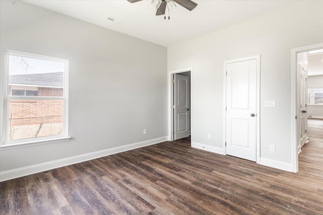 unfurnished bedroom featuring visible vents, baseboards, dark wood-type flooring, and a ceiling fan